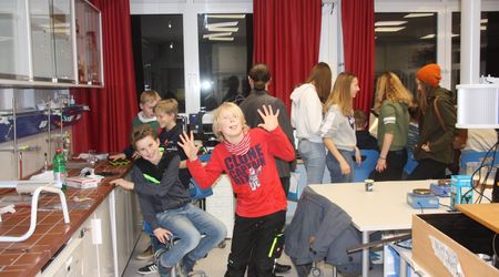 Schülerinnen und Schüler beschäftigen sich mit verschiedenen Experimenten am Tag der offenen Tür im Schülerforschungszentrum des Gymnasiums Marne (Standort Dithmarschen Süd) und lachen mit Faxen in die Kamera